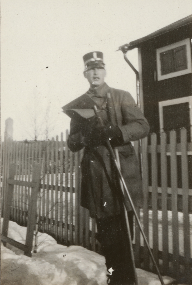 En soldat på skidor läser kartan framför en byggnad. Porträttbild av Christer Wahlgren som deltog i stridsvagnskursen vid Göta livgardes stridsvagnsbataljon år 1928-1930.
