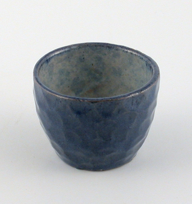 Drejad rund kopp med tummad utsida. Blå glaserad. Gråmelerad inuti med gul, blå och grön dekor.