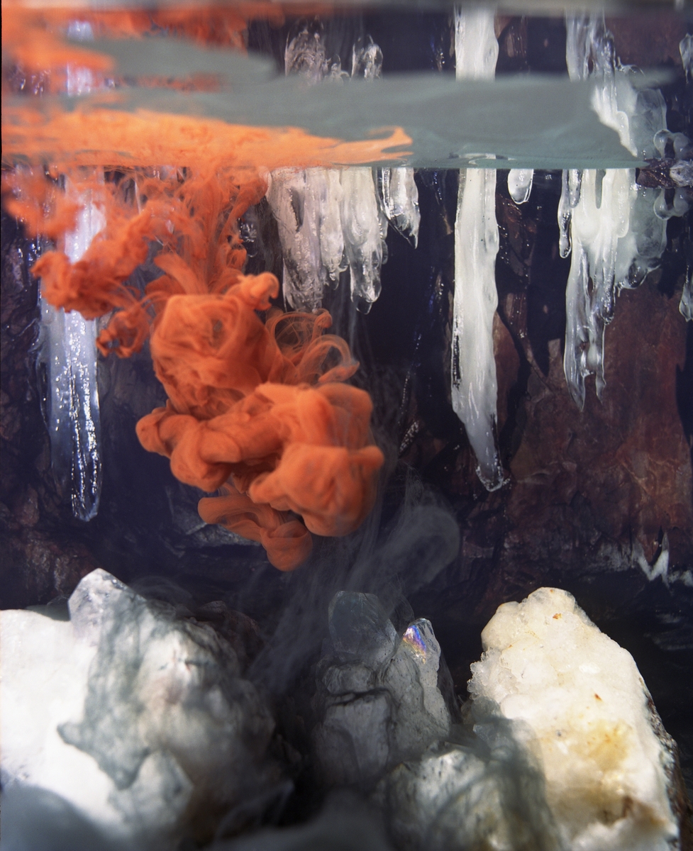 Fotografiet viser fargepigmenter som oppløses i et akvarium. I tillegg sees ulike krystaller og mineraler.