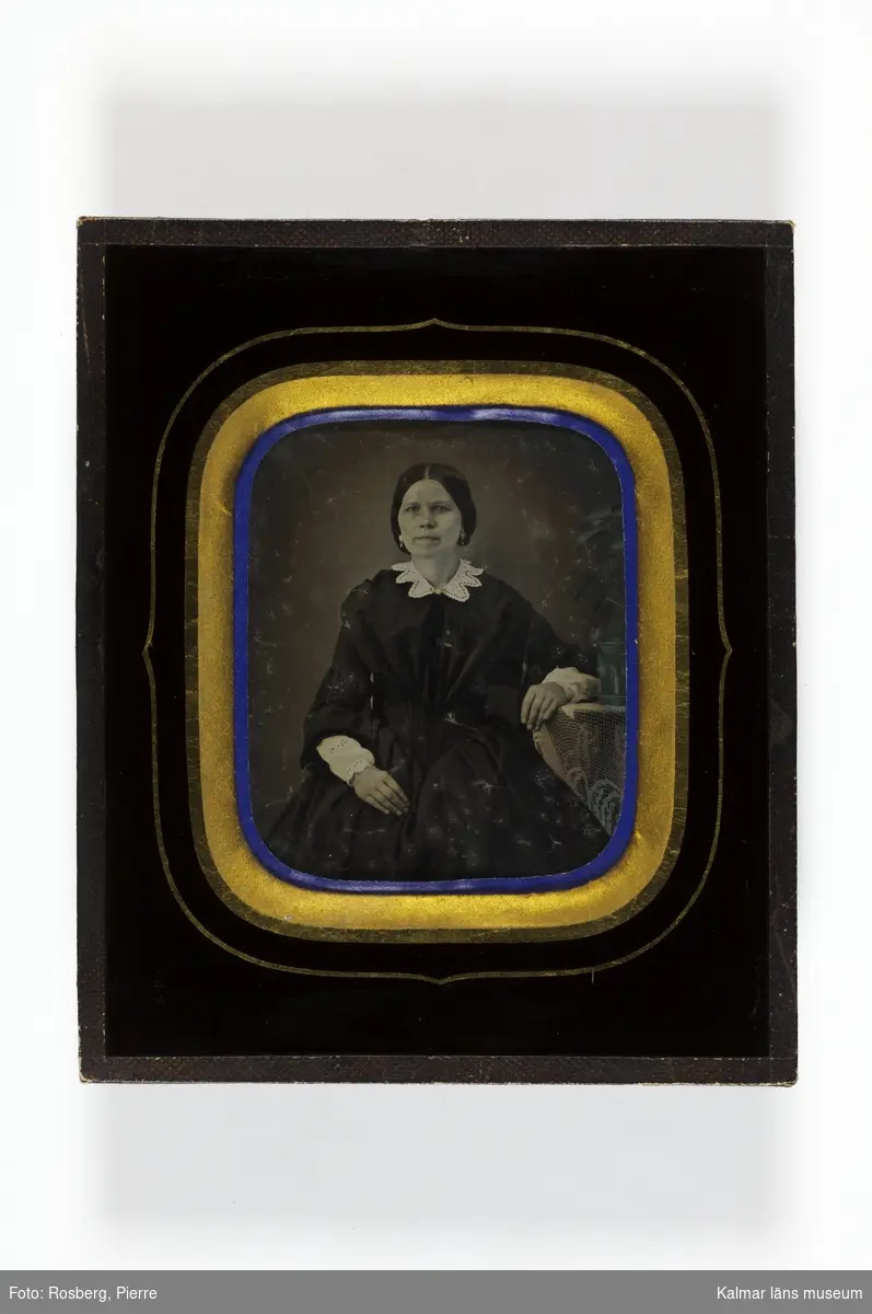 Porträtt av kvinna, fru Dahlgren, som sitter vid ett bord, med vänster arm på bordet.
