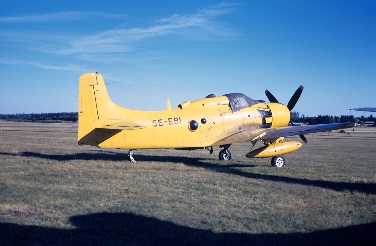 Civilregistrerat flygplan Douglas Skyraider AD-4W med märkning SE-EBI står på flygfältet på Malmen, hösten 1973. Serie om 3 bilder.
