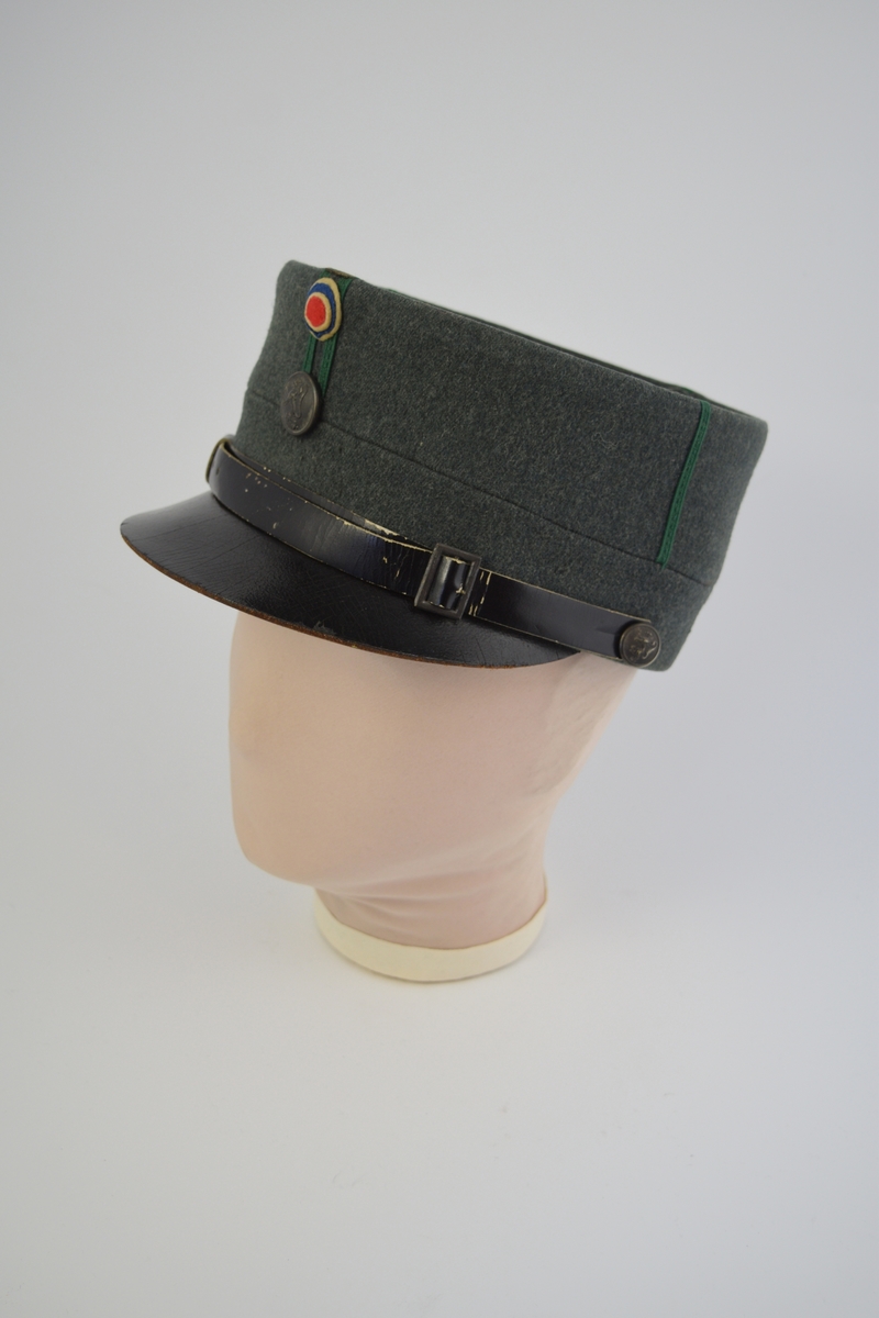 Uniform i tre deler: jakke, lue og patronveske. Innsvinget jakke med fire lommer,enkelt spent,nedbrettet krage. Bøtteformet lue med distinksjoner. Svart lærbrem og svart lærrem som går over bremmen. Kvadratisk patronveske i grønt lerretsstoff, med stor svar trykknapp foran.