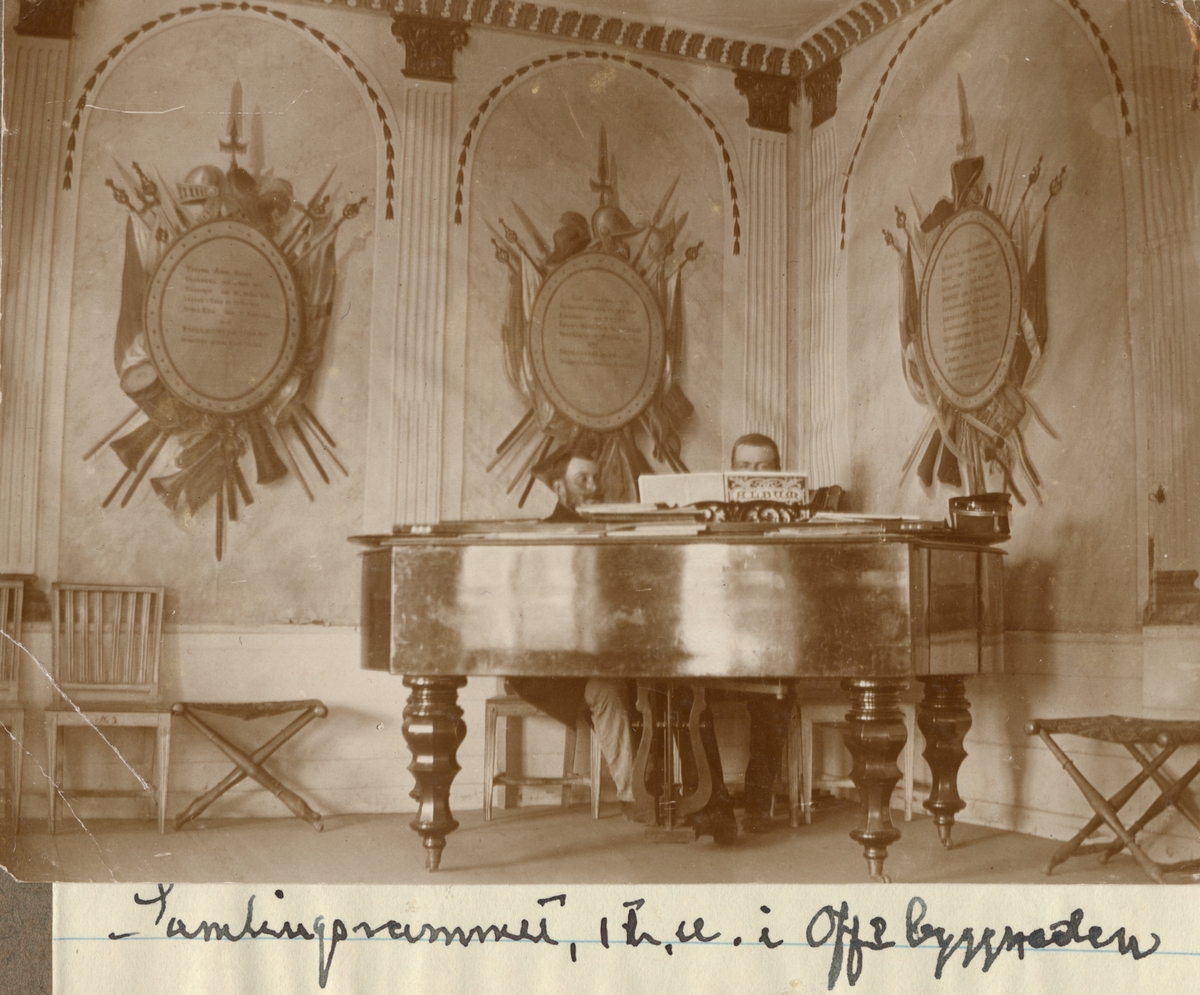 Två män bakom piano i Hälsinge regementets samlingsrum.