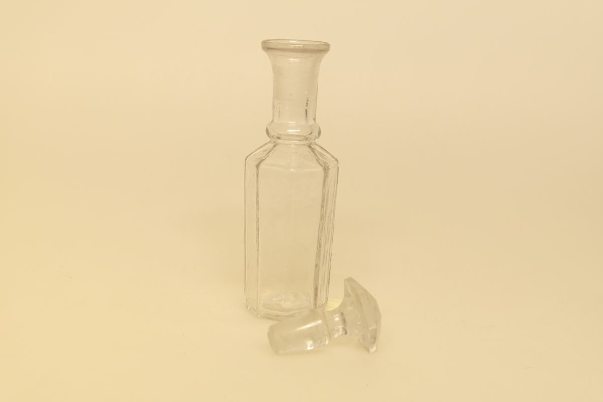 Kryddersett bestående av stativ (a), tre glass (b-e) og skje (f).
A) Krydderstativ av løvtre og støpt messing. Stativet er saget, høvlet, pusset og lakket. Messingkant rundt tre sirkelåpninger. Balusterformet håndtak med ring i messing i midten av stativet. Tre messingbein formet som dyreføtter.
B) Støpt glass med glasspropp (E)
C) Støpt glass med gjennomhullet messingkork
D) Støpt glass
F) Skje i bein som er skåret og pusset