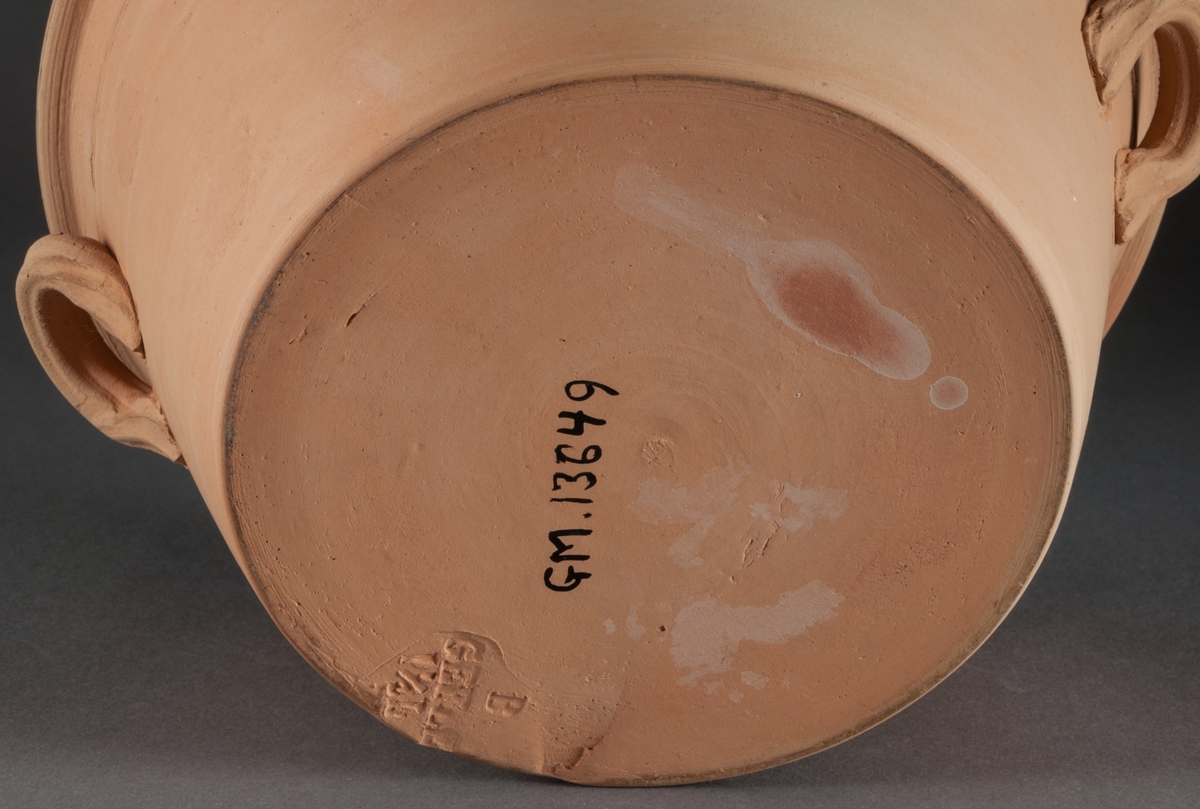 Spillkum, Bo Fajans, med två öron, utvändigt oglaserad, invändigt gul glasyr. Diam. 20,5 cm. Höjd 10,5 cm.
Prov på fabrikens äldsta tillverkning. 1880-talet.