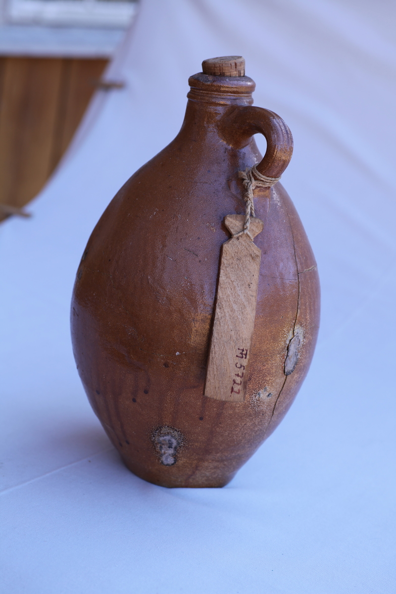 Nyreparert, flere enkeltbiter limt sammen, brun. Hanke øverst oppe, elegant form, kork mangler