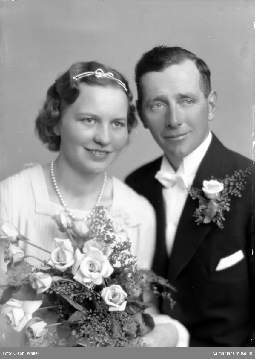 Bröllopsbild. Bruden har diadem, brudbukett och ett pärlhalsband. Mannen har corsage. Enligt Walter Olsons journal är bilden beställd av Gustav Pettersson.