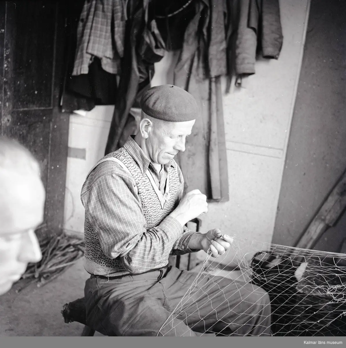 En man som lagar ett fiskenät på Stensö fiskeläge.