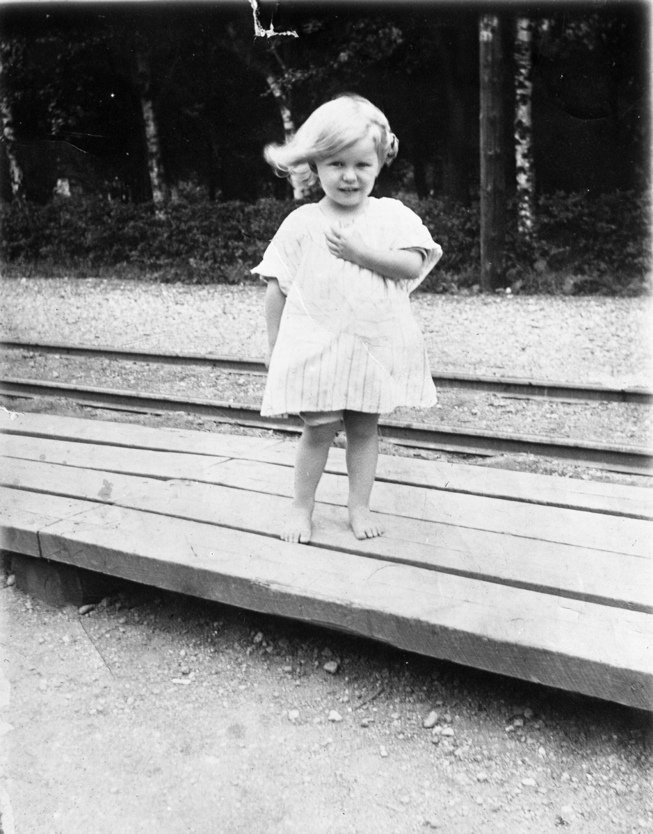 Reprofotografi av liten flicka med vind i håret vid järnvägsstation.