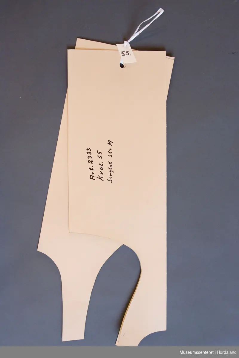 Mønsterskantar i papp, brukt til å skjere ut ulike delar av plagg i klesproduksjon. Desse er til ein singlet, art. 2333, kval. 55, str. M.