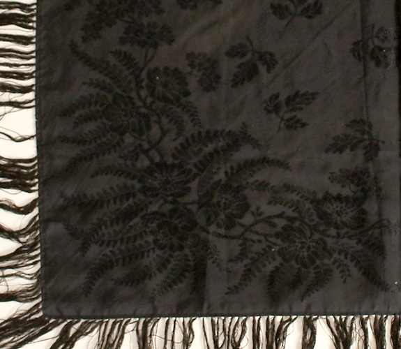 Svart jacquardvävd silkeschal med iknutna fransar, ca 13 cm långa.
Stämplad "K Almgren Stockholm".

Har varit vikt diagonalt, svag blekskada finns