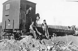 Menn, spader, jernbanebu på spor.