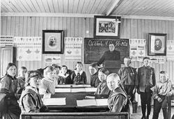 Personer, klær, skolepulter, tavle, kateter, bilder.