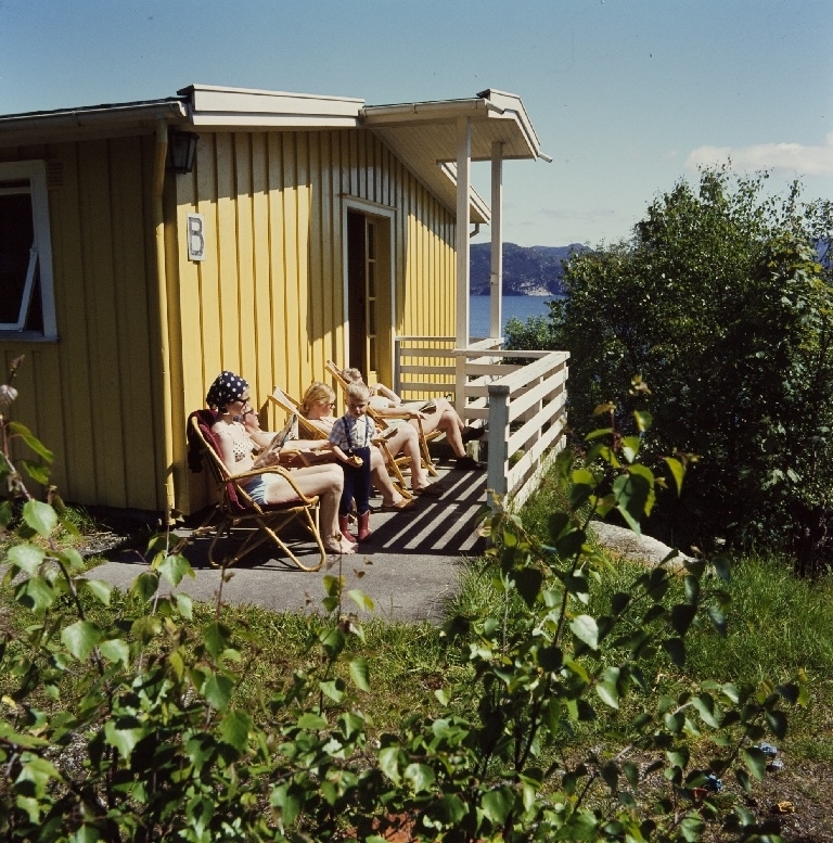 Familie på verandaen utenfor feriehjemmet nr. 5 til bedriften Jonas Øglænd Sandnes på Bersagel