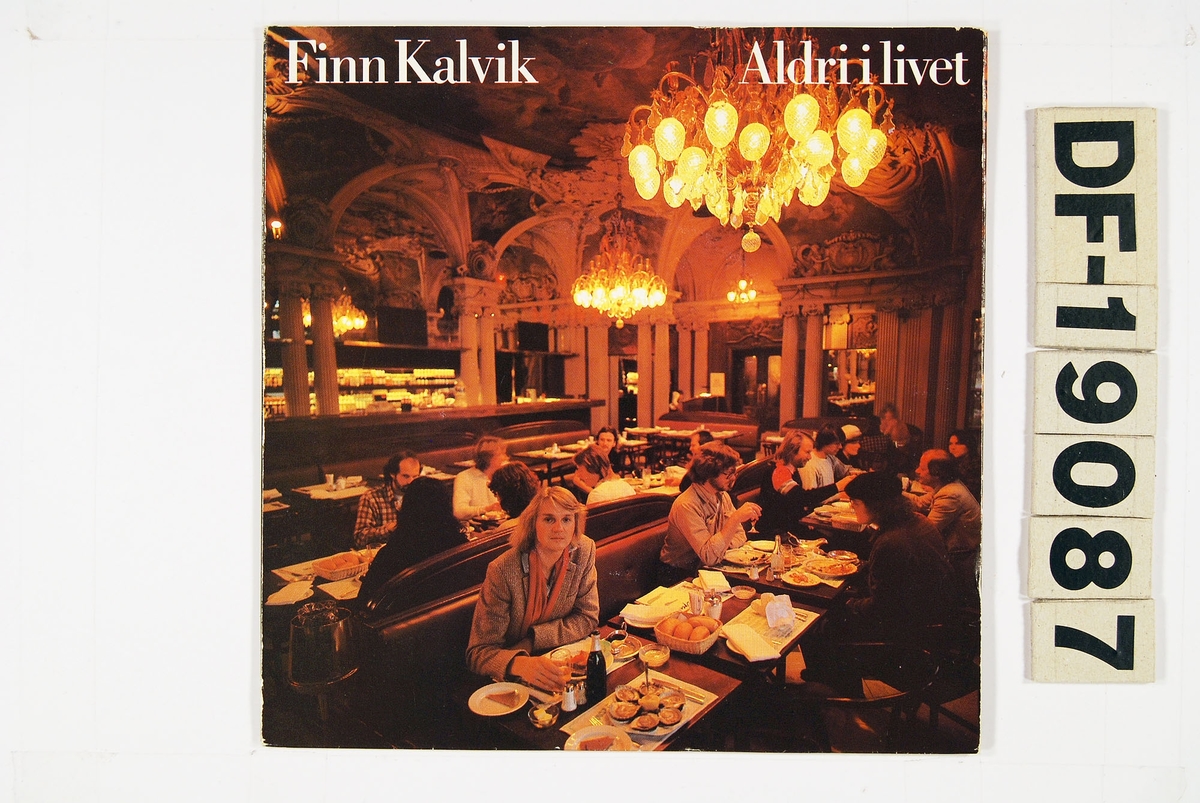 Bilde av en restaurant med masse folk rundt bordene. Ved det nærmeste bordet sitter Finn Bjørn Kalvik og ser inn i kamera.