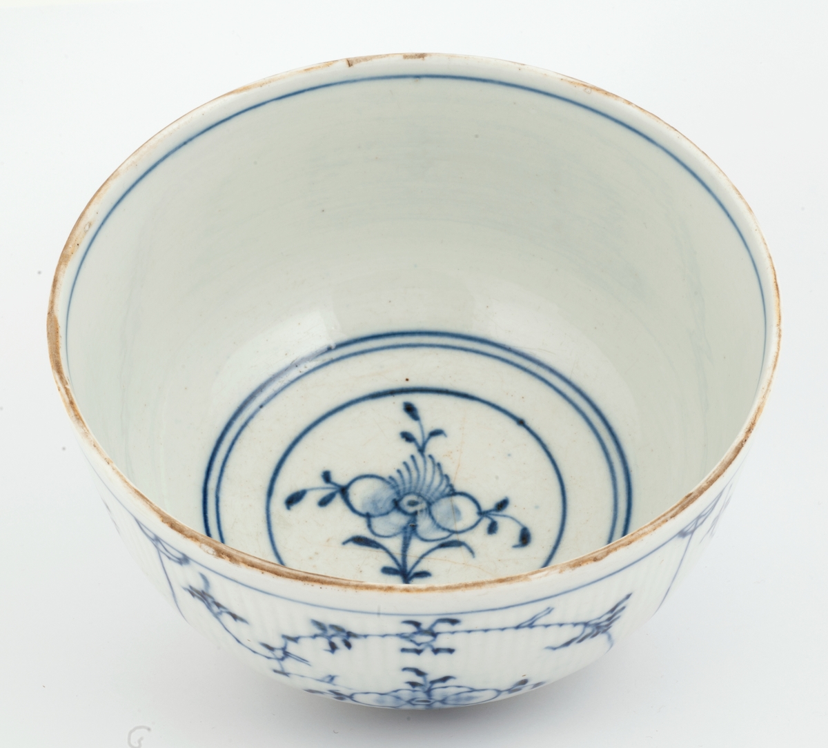 Skål i hvitt porselen med riflet gods og blått musselmalt mønster.
