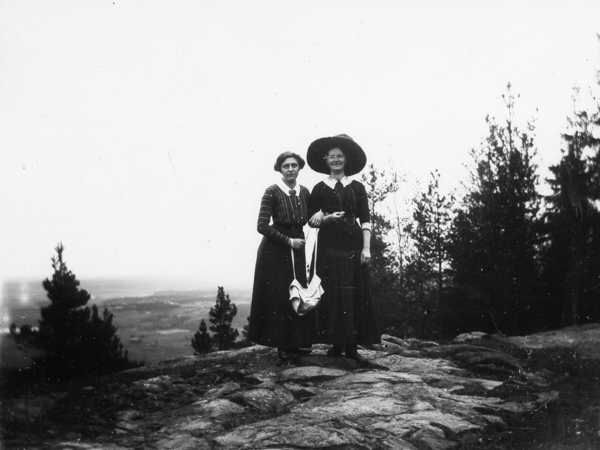 Två damer med väska på bergstopp.