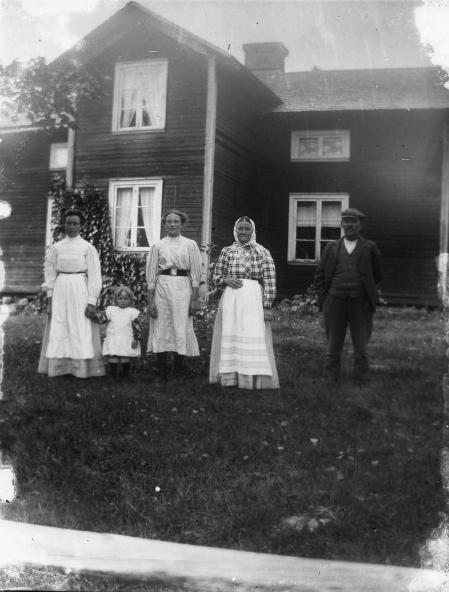 Fyra vuxna och ett barn poserar framför bostadshus.