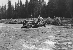 Menn med traktor prøver krysse en elv. Lidvin Solberg og Kar