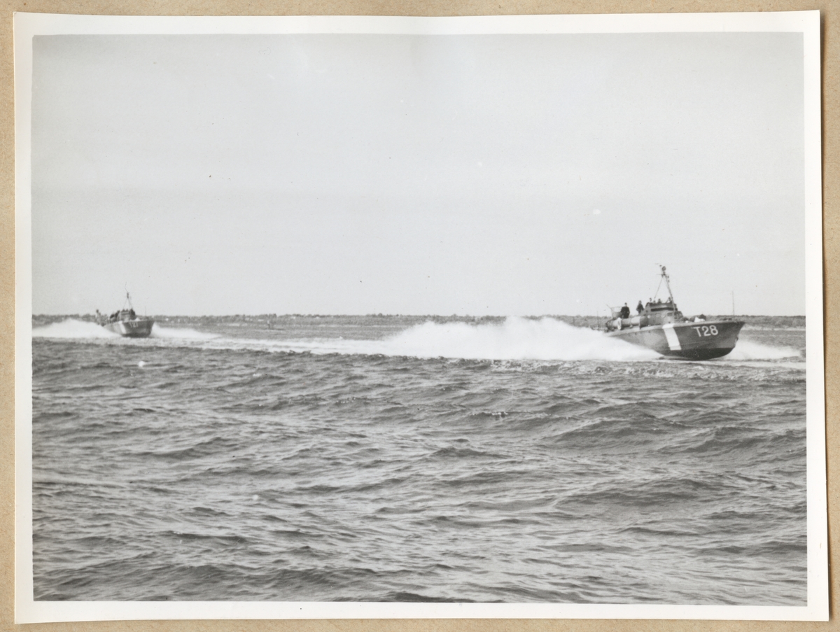 Motortorpedbåtarna T 28 och T 27 syns färdas i hög hastighet på vattnet. I bakgrunden syns land.