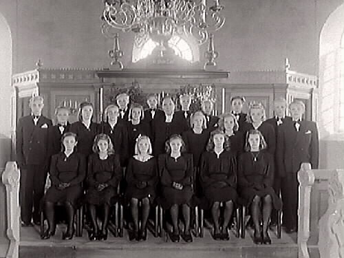 Konfirmandgrupp i koret med prästen Wetterkvist i mitten.