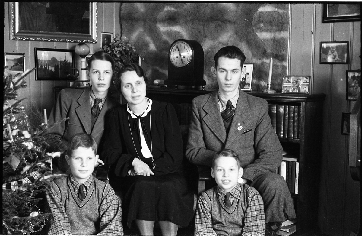 Ifølge fotografens notat: "Familien Larsen". Mor og sønner var bosatt på Sukkestad under krigen mens ektemann/far, som var engasjert i hvalfangst, var tvunget til utlendighet under hele krigen. Mors fornavn er ukjent, mens guttene er (plassering iht. bilde nr. 1): Bak til venstre Karl Anton, og til høyre Odd. Foran til venstre Einar, mens navnet på han til høyre er ukjent.,  Serie på 11 bilder.