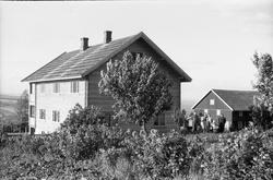 Fra gården Kae i Østre Toten. Noen personerstår mellom bygni