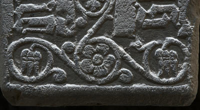 Detalj fra en middelaldergravstein; en flott uthugget fembladet blomst med bladranker rundt. (Foto/Photo)