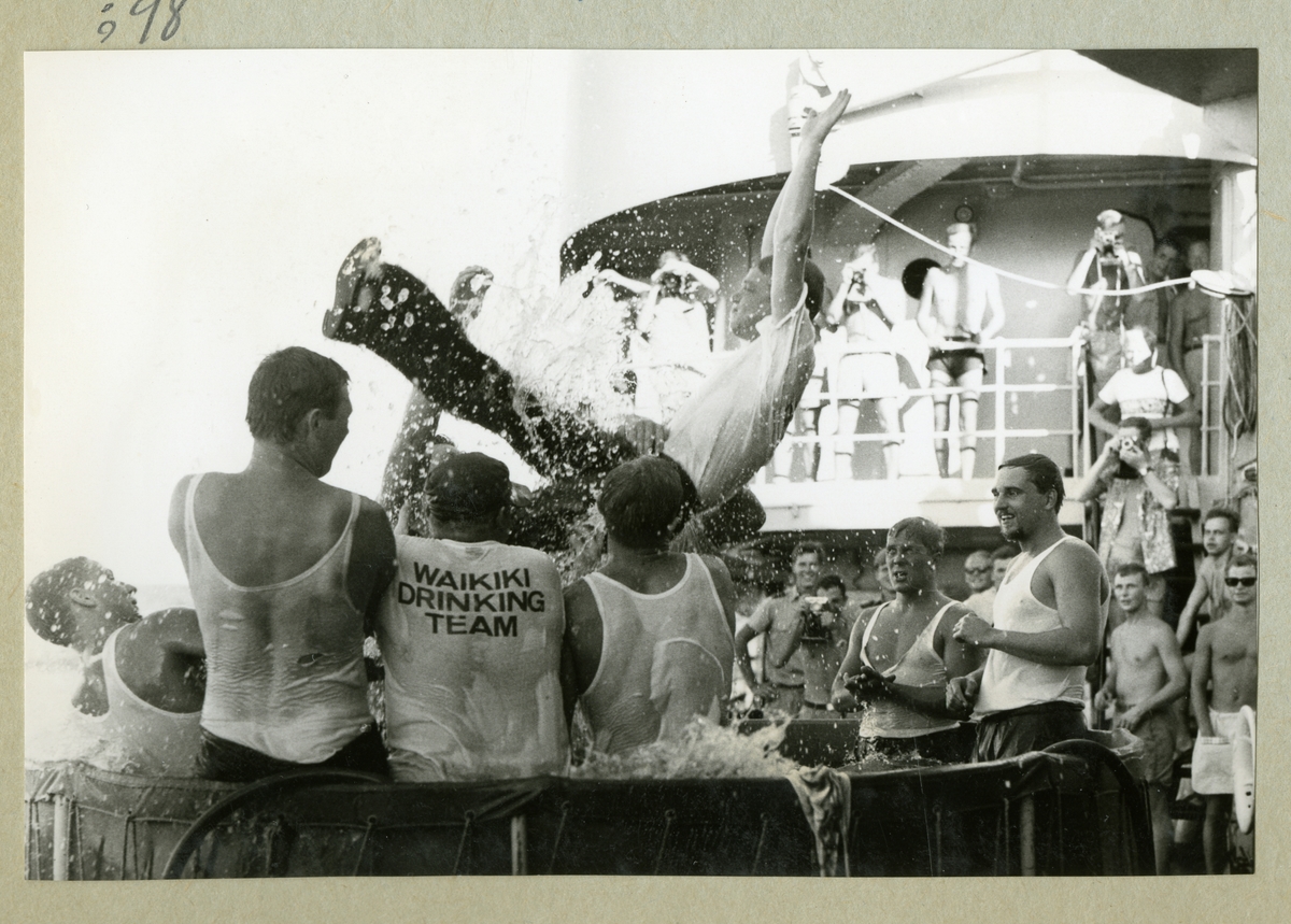 Bilden föreställer flera besättningmän i en liten vattenbassäng ombord på minfartyget Älvsnabben. I bakgrunden syns ytterligare besättningsmedlemmar som åskådare till badet. Bilden är tagen i samband med fartygets långresa 1966-1967.