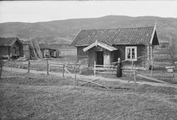 Dame stående foran husmannsplass på Kaasa i Heddal.