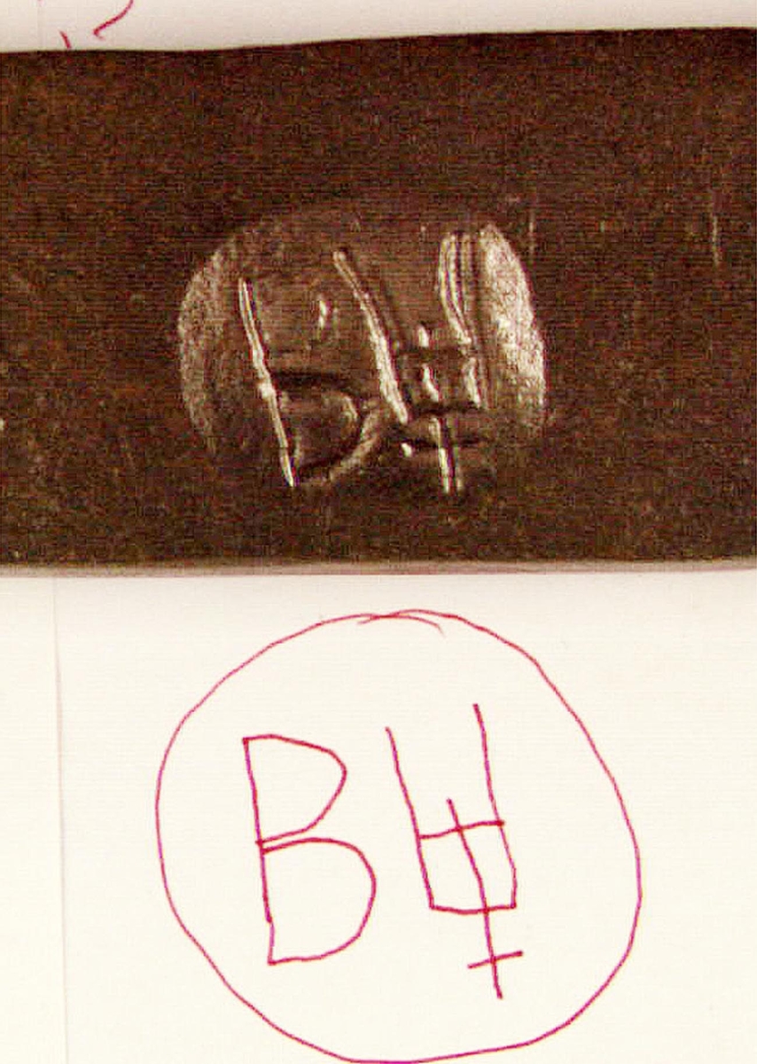 En bit av ett stångjärn försedd med stämpel, ett B och ett U i rundel.