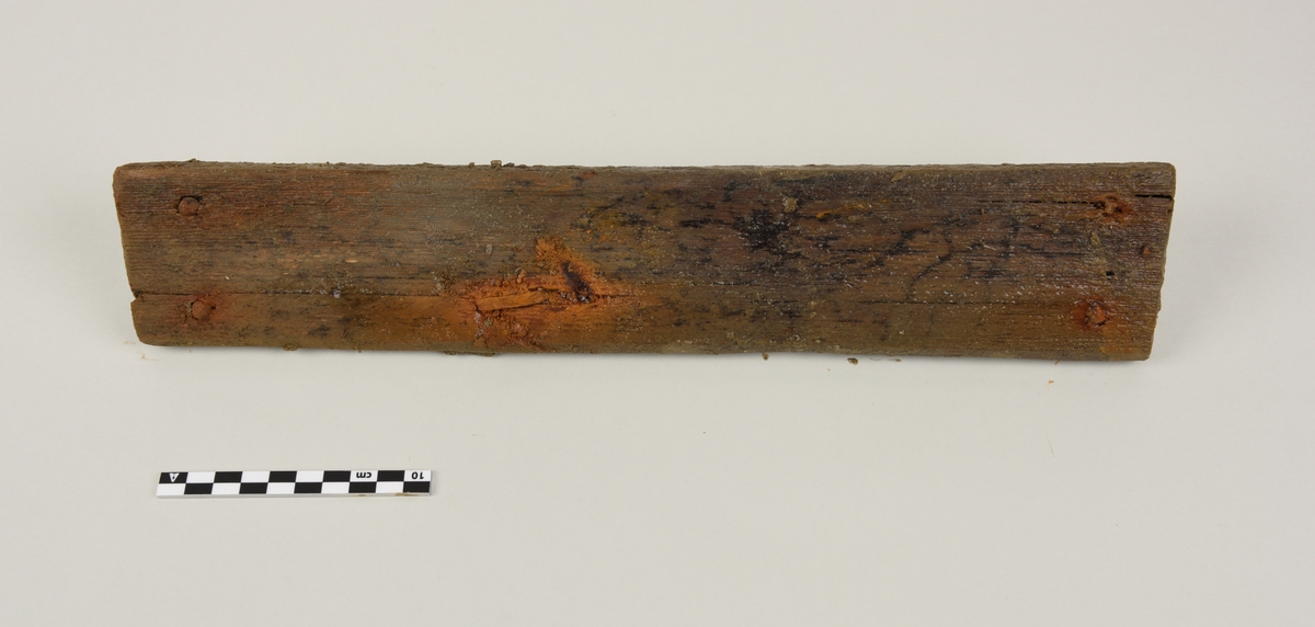 Deler av en rektangulær gravkiste.
Det er 4 avlange rektangulære treplanker og tverrplanker fra kisten. Hver er laget av ett stykke tre. Det er rester etter spiker og misfarging på grunnen av rust.