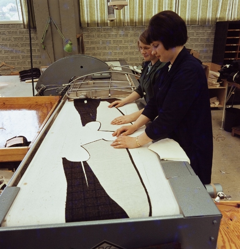 To kvinnelige arbeidere limer viselin-innlegg i en jakke med en klebepresse i konfeksjonsfabrikken til Jonas Øglænd Sandnes.
