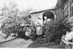 Personer foran bolighus, mye beplantning. 
Nordistu-Unset i