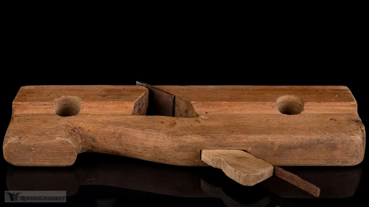 Smal rektangulær høvelstokk med tilskåret horn i forkant og avrundede hjørner. To gjennomgående opphengshull. Stokken er skåret slik at det er en støttekant ved siden av sålen. Gaffelformet høvelblad der et spor går langs sålen mellom de to tennene for høvling av fjær.