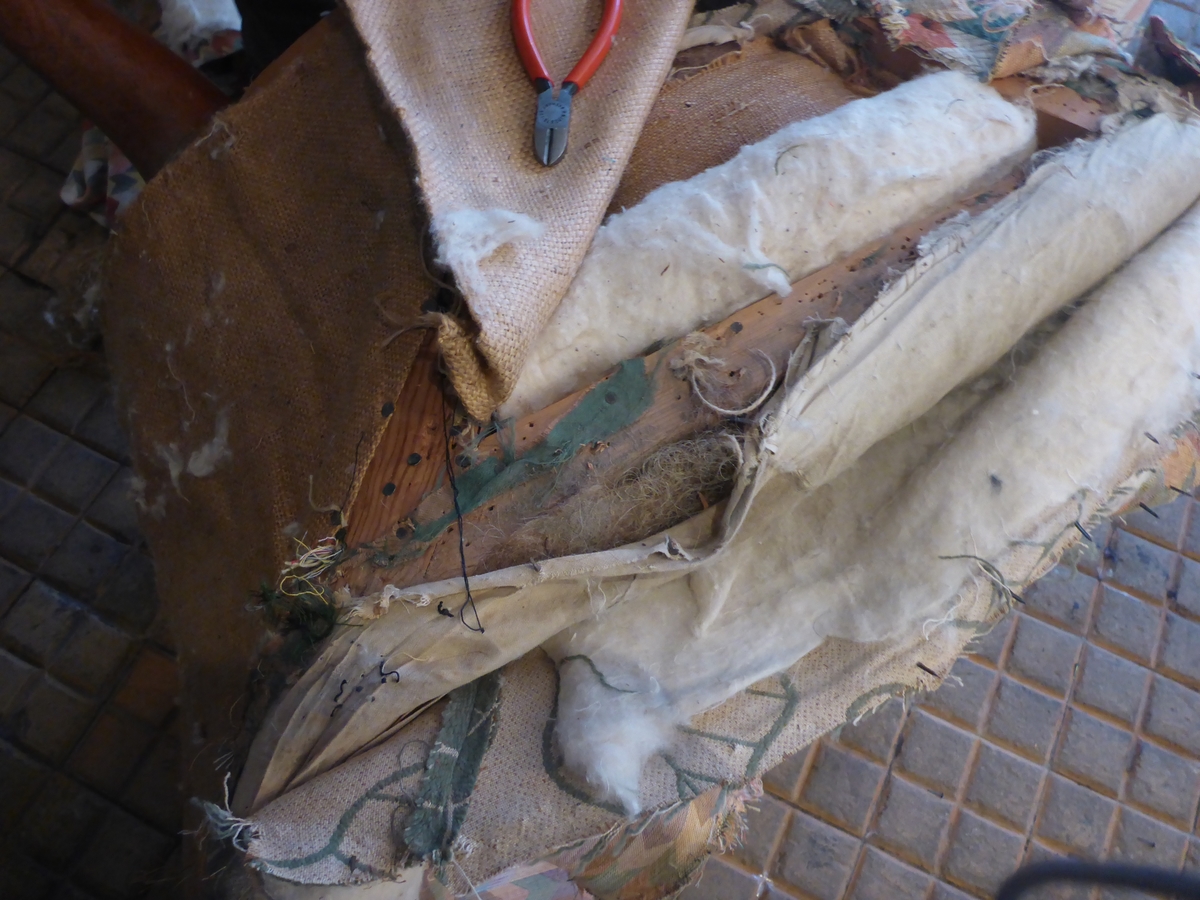 Stolen har en ramme av tre med dreide frambein som er beiset og oljet.