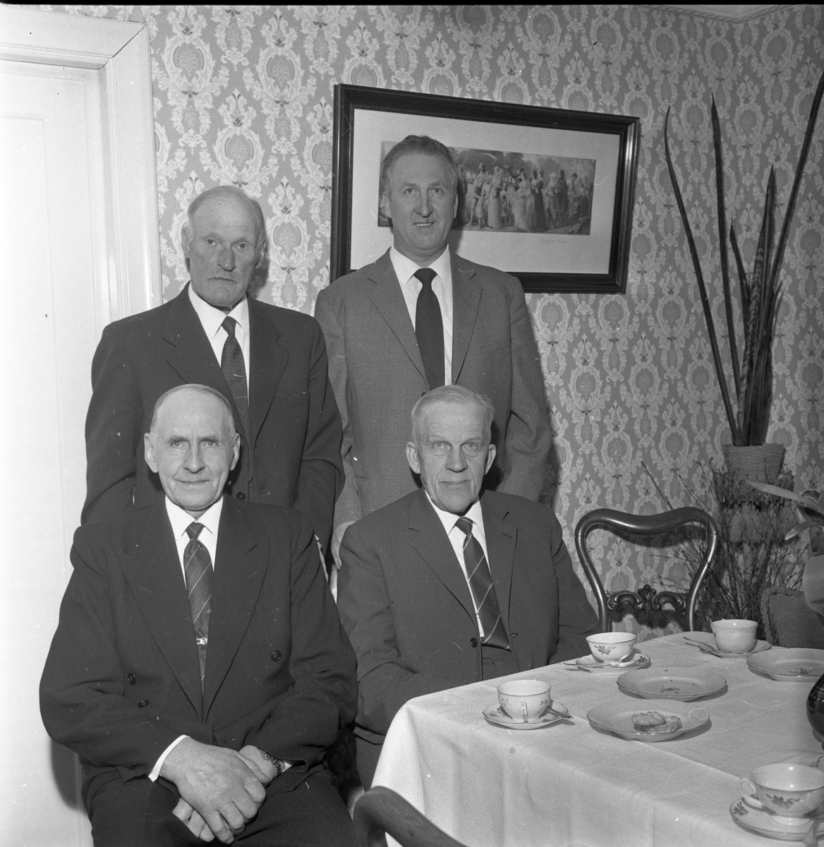 Ölmstads byalag, mars 1964. Ett dukat kaffebord med (fr vänster) Arvid Jansson och Gunnar Gustafsson sittande samt David Larsson och Carl Svanström stående.