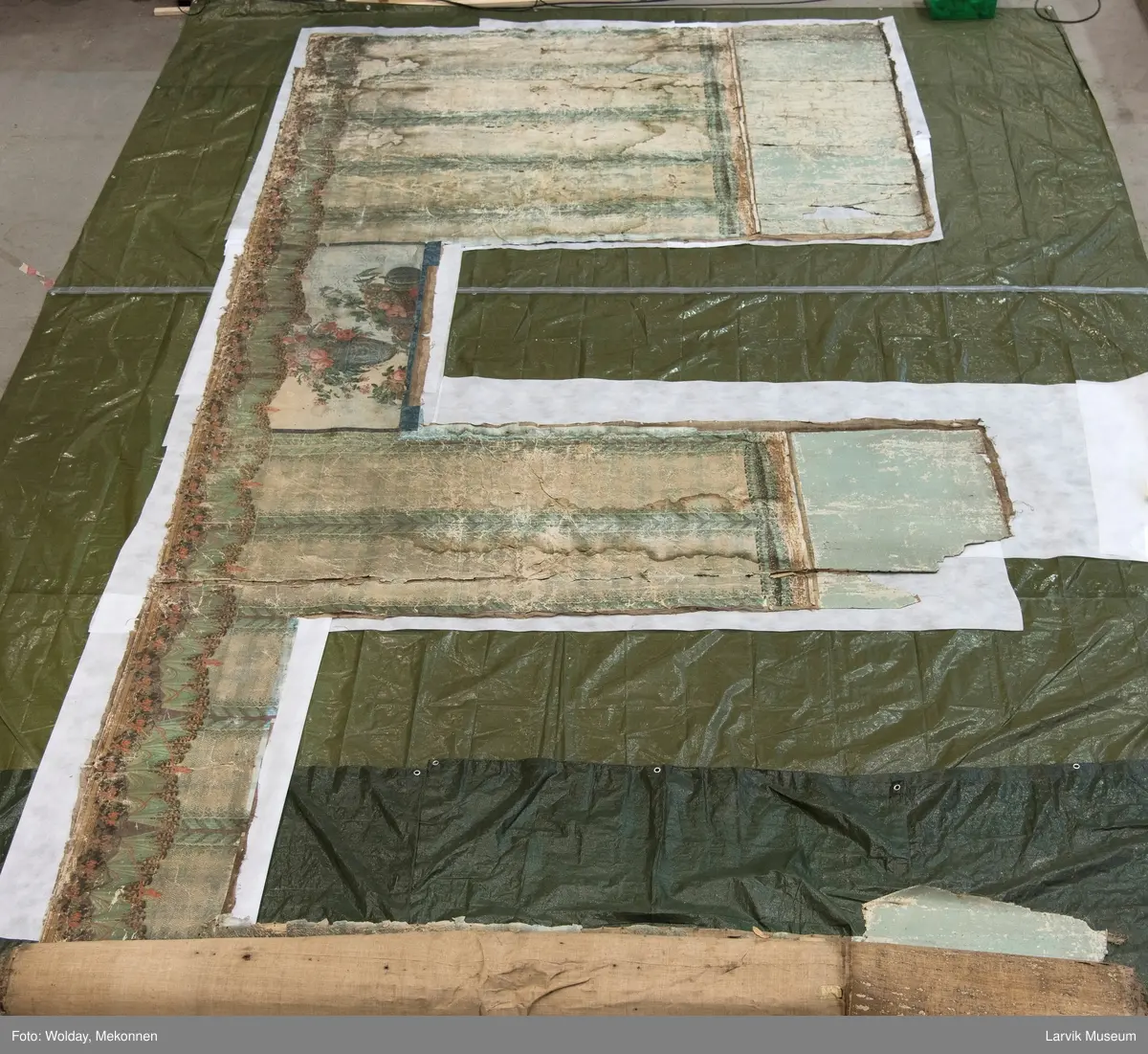 |Tapeten er påmalt tapetborder og brystning. Fra Hovland gård i Larvik.
Den øverste, brede borden: Gerlander/draperi med blomsterranker.
Den nederste, smalere borden: Tekstilbord med blomster. Øver døren til høyre: Stillebenmotiv med blomster og frukt.