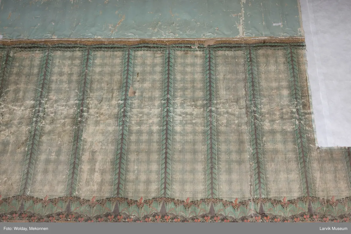 |Tapeten er påmalt tapetborder og brystning. Fra Hovland gård i Larvik.
Den øverste, brede borden: Gerlander/draperi med blomsterranker.
Den nederste, smalere borden: Tekstilbord med blomster. Øver døren til høyre: Stillebenmotiv med blomster og frukt.