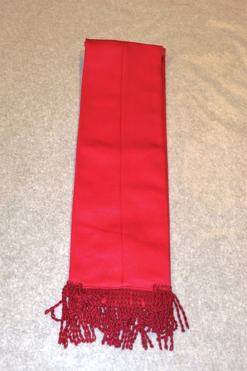 Jakke (a): blå polyester med for av blå kunstsilke. Rød krage og slag og oppslag på ermene. 3 blanke knapper. Røde epauletter med blanke knapper, rød pyntesnor rundt høre arm
Bukse (b): blå polyester, røde render i sidesømmene. Nylon glidelås i gylfen. 1 svart knapp
Magebelte (c), rødt, blankt kunstfiberstoff, foret med rød bomull. 3 folder midt på. Lukkes med borrelås. 91 l, 11.5 b
Pyntesløyfe (d), samme tøy som beltet. Røde frynser i nedkant. Kan festes med borrelås til belte. Todelt. 49 l, 12 b.