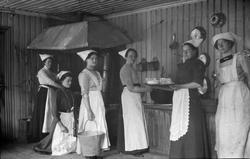 Gruppe jenter med skaut i kjøkkenet.  Kurs ved amtskolen i B