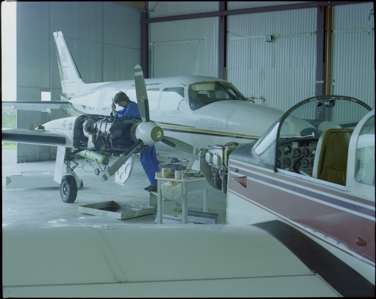 En mann utfører service på et av "Coast Aero Center" sine småfly i en hangar på Helganes.