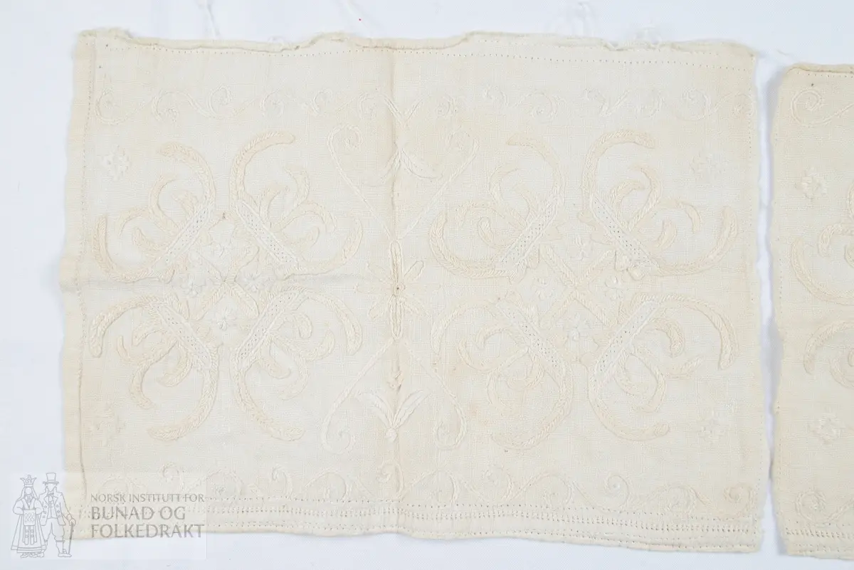 Delar av ein hovudklut. To rektangulære stykkjer av kvit blank lett lin. Kontursting, klostersting og vestmannarenning. Holfaldar. Brodert med kvit laistvinna lintråd.