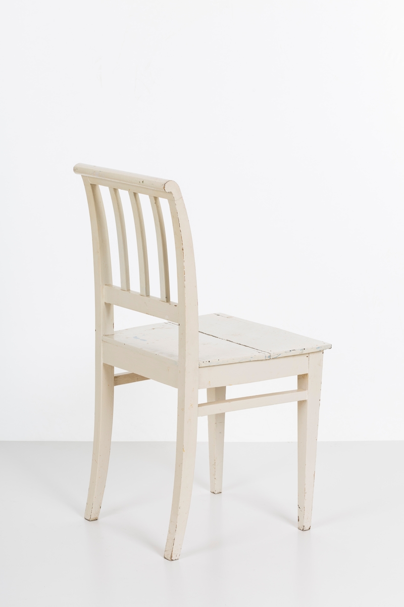 Hvitmalt spisestuestol. Sprosser i rygg og mellom stolbeina på venstre og høyre side.