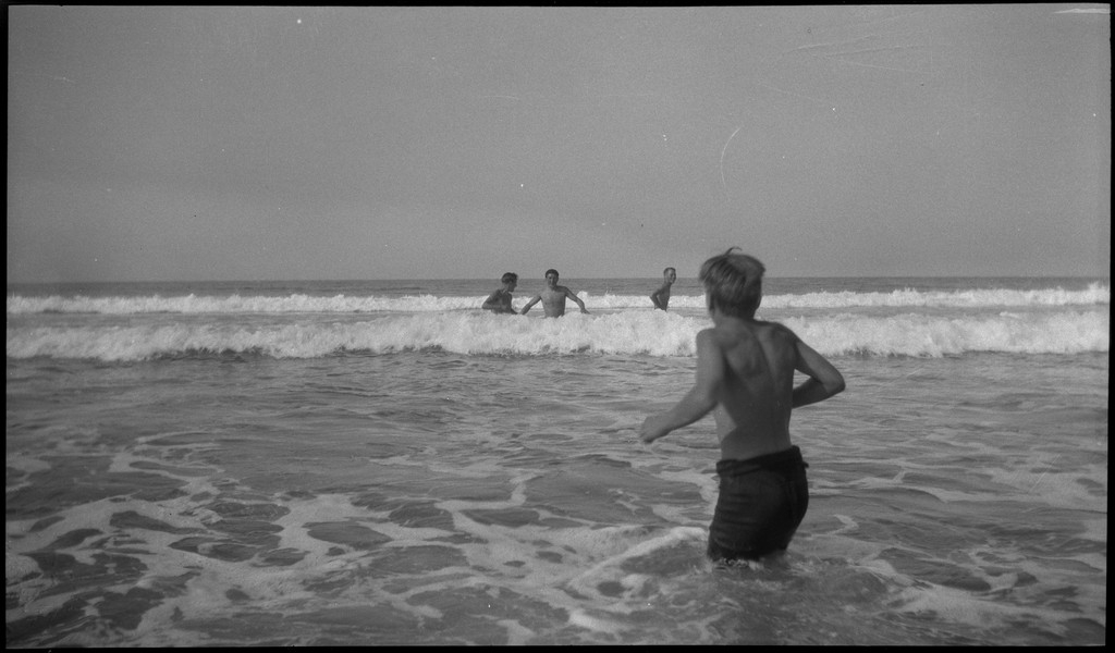 4 unge menn er ute og bader på en sandstrand med sanddyner.