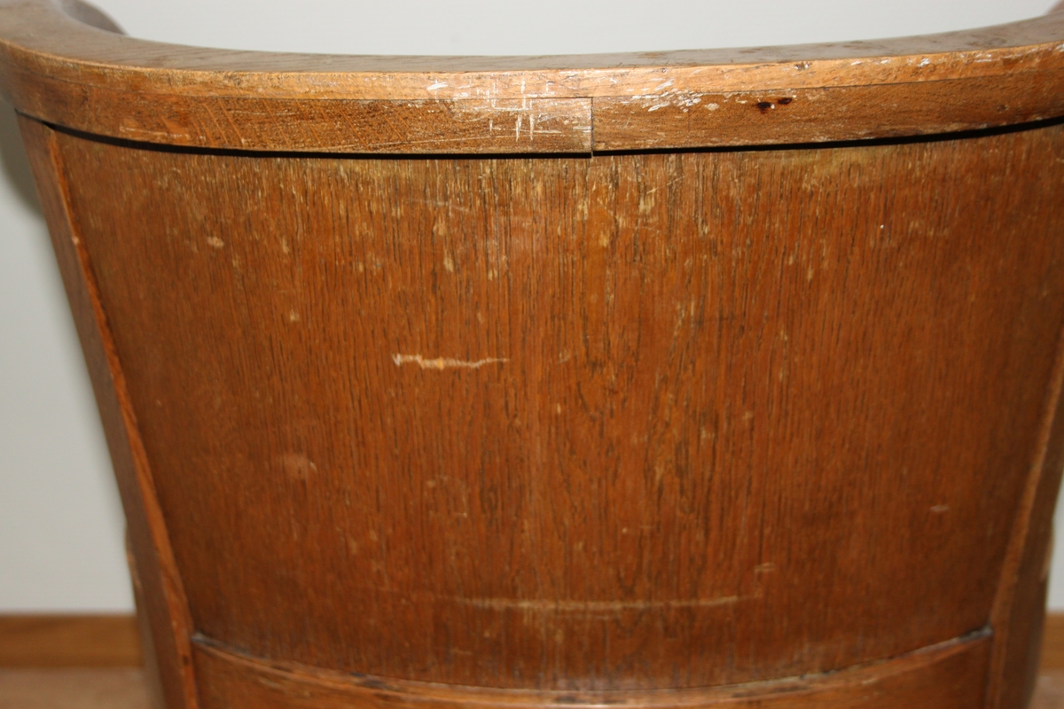 Møteromstol/kontorstol med armlener samt buet rygg. 4 ben. Metallbeslag under armlener. Brunt skinn i rygg og sete. Stolen er lakket med klar lakk. Originalt møbel innkjøpt til det nye Statsarkivet i Kristiansand i 1935.