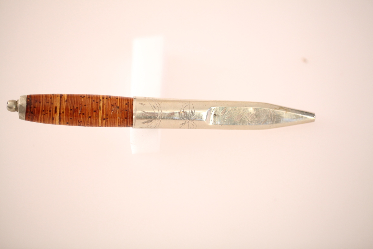 Kniv og slire hører ikke sammen. skaftet er laget av never, og slira er laget av nysølv. vanligvis hadde neverskaftkniver lærslire, og nysølvslirer hadde vanligvis ibenholdtskaft. Dekoren på slira er gravering og motivet er såkalte "Elstadkvister" slira er dermed høyest sannsynelig laget i Kolbu av en av Elstadkarene. Kniven har et fabrikkblad og er av ukjent opprinnelse.