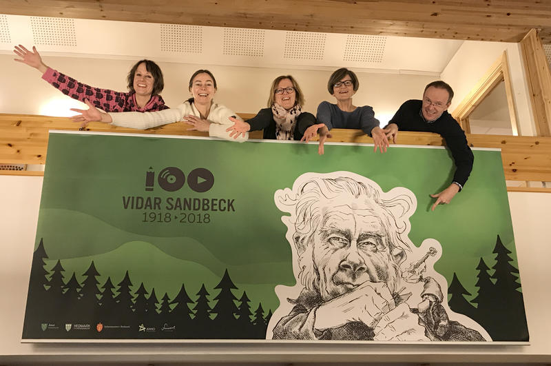 Ansatte ved Kulturkontoret i Åmot kommune bak banner med Vidar Sandbeck-jubileet. (Foto/Photo)