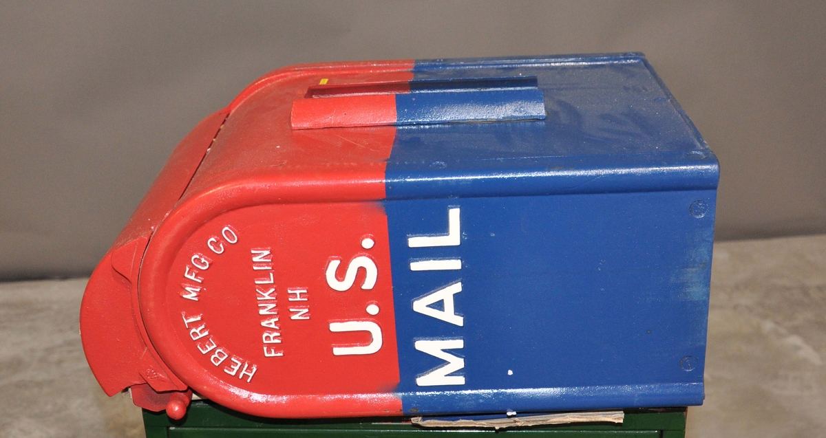 Rød, hvit og blå postkasse av jern med avrundet topp.