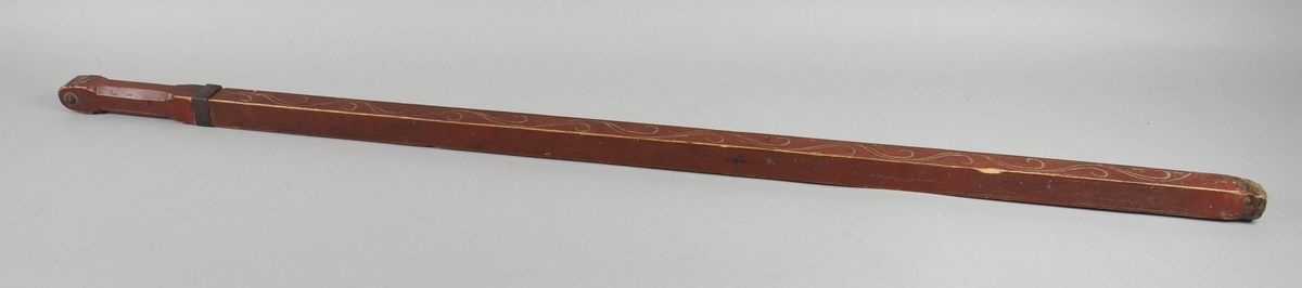 Målestokk av tre der tommestokken - som har to ledd - trekkes ut av den ytterste hylsen. Hylsen er dekorert med en bord / ranke. Kanten på hylsen er forsterket med metall.